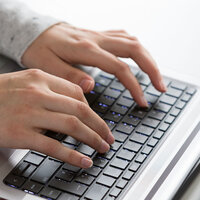 an einem Laptop tippende Hände