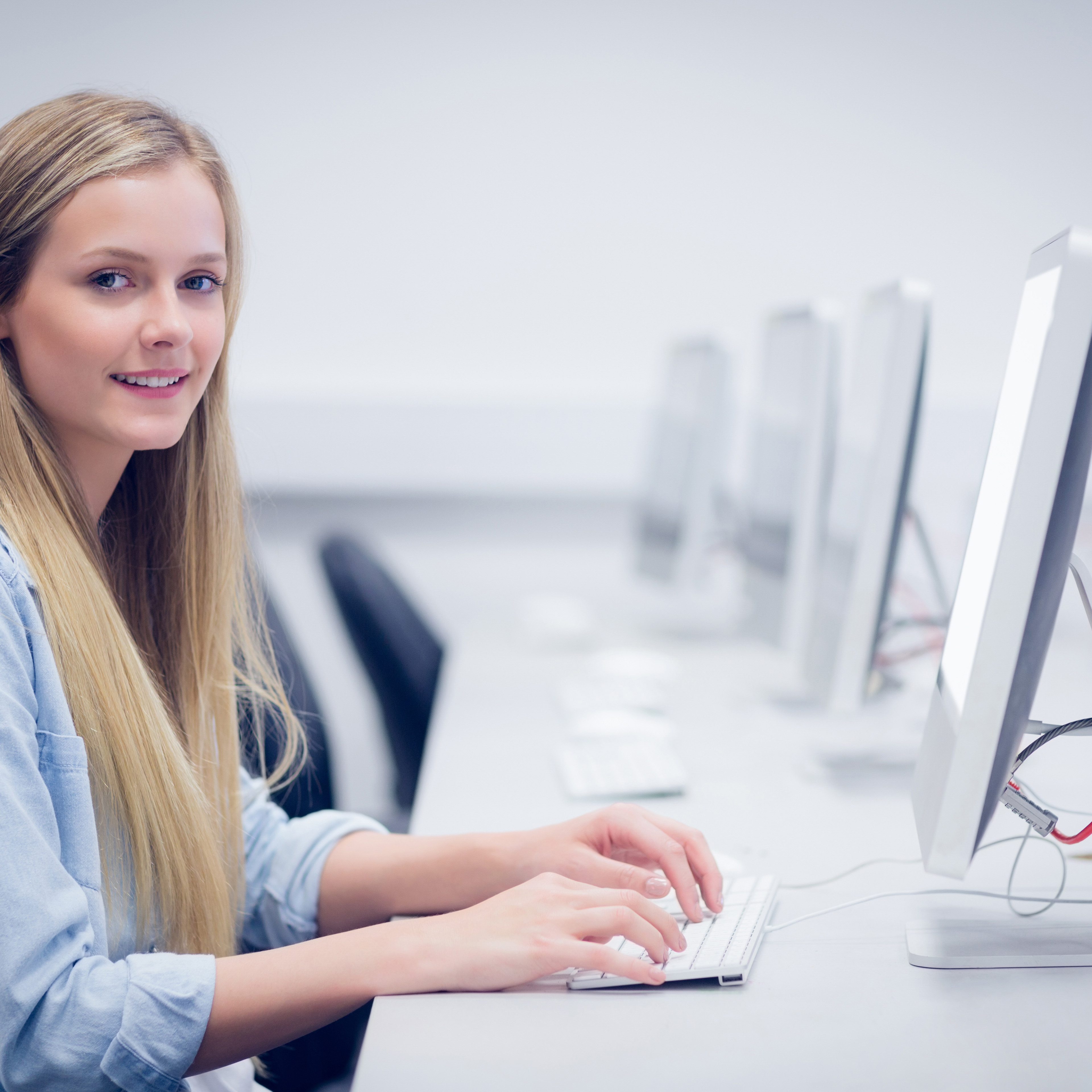 Eine junge Studierende sitzt in einem Computerraum und schaut von ihrer Tastatur auf.  istockphoto-845858906-1024x1024_1-1-gd.jpg